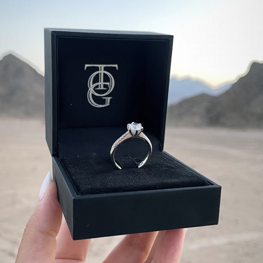 anello 6 griffe con diamanti firmato Torinogioielli fotografato nella sua scatola con sullo sfondo un romantico deserto.