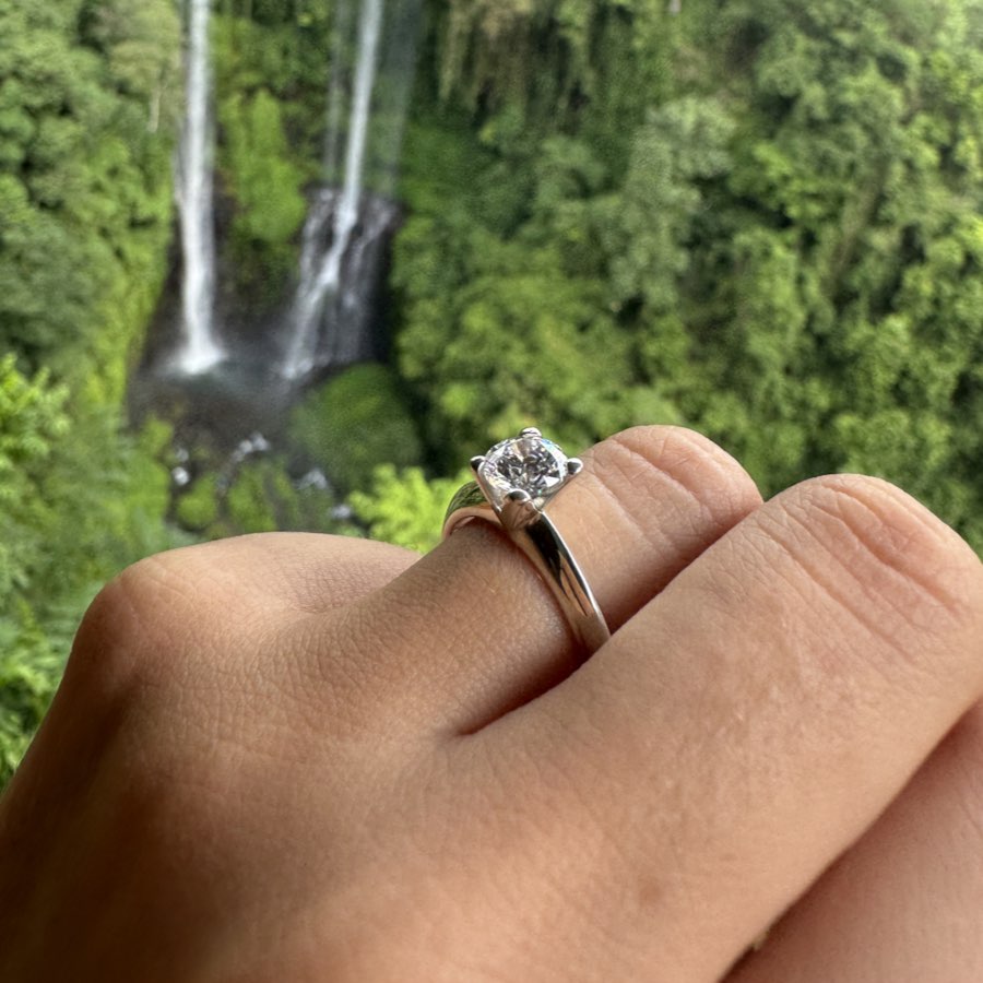 anello con diamante solitario indossato dopo la proposta di matrimonio in mezzo alla natura nei pressi di una romantica cascata.